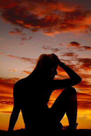A silhouette of a woman in despair sitting and thinking.の写真素材