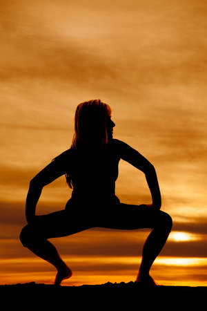 A silhouette of a woman doing a yoga stretch in the outdoors.の写真素材