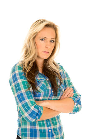 a woman in her blue plaid shirt with a serious expression on her face, with her arms folded.の写真素材