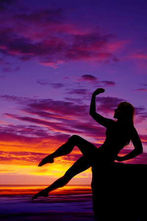 A silhouette of a woman balancing on a cliff.の写真素材
