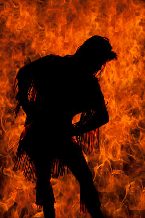 a silhouette of a woman in her Native American costume with a fire background.の写真素材