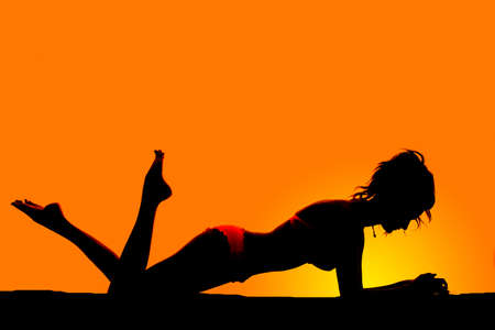 A silhouette of a woman in a bikini laying out in the outdoors.の写真素材