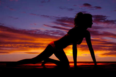 a silhouette of a woman crawling on the ground in her bikini.の写真素材