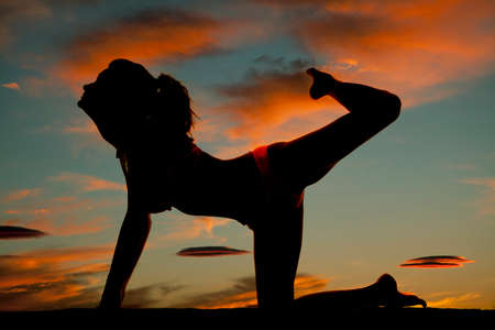 A silhouette of a woman in her bikini with her leg up.の写真素材