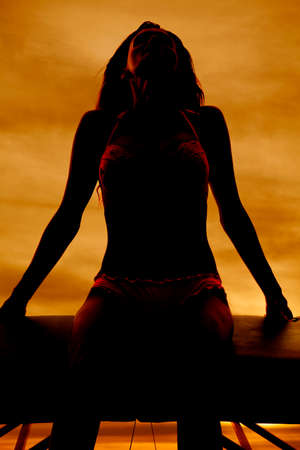 a silhouette of a woman sitting with her head back.の写真素材