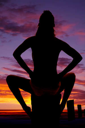a silhouette of a woman sitting with her back to the camera in her bikini.の写真素材