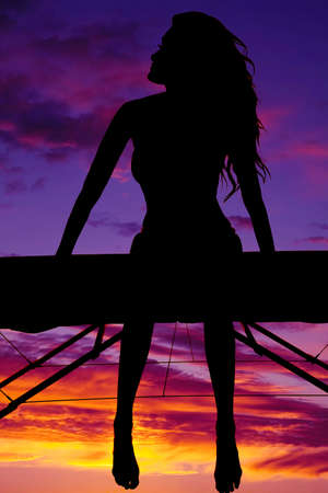 a silhouette of a woman sitting and relaxing in her bikini.の写真素材