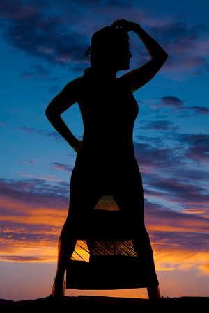 A silhouette of a woman in her dress with her hand on her head.の写真素材