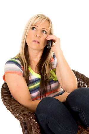 a woman sitting in her chair on her cell phone, with a sad expression.の写真素材
