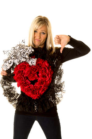 A woman holding on to her heart wreath with her thumb pointing down.の写真素材
