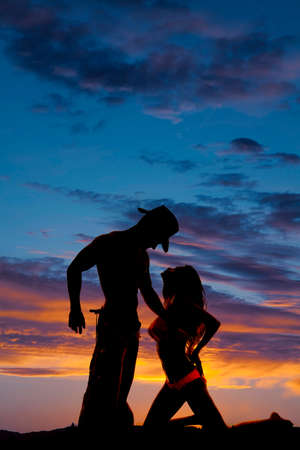 A silhouette of a woman on her knees looking into her cowboys face.の写真素材