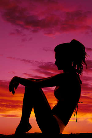 A silhouette of a woman in her bikini curling up relaxing.の写真素材