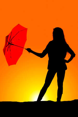 A silhouette of a woman holding out her umbrella.の写真素材