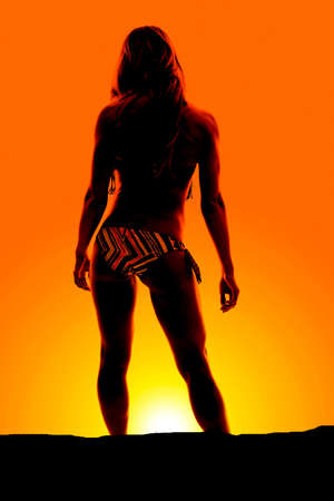 a silhouette of a woman with her back to the camera, in her bikini.の写真素材