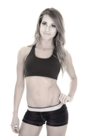A fit woman with a small smile, posing in her sports bra and shorts.の写真素材