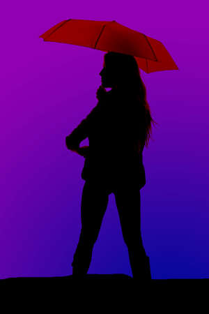 A silhouette of a woman staning with an umbrella in her hands.の写真素材