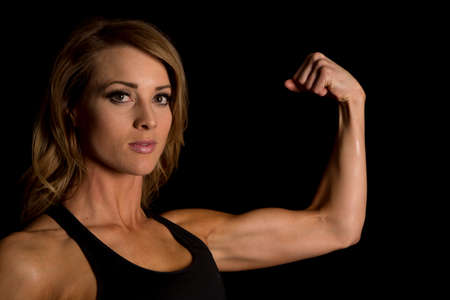 A woman up close, flexing her arm showing her toned muscles.の写真素材