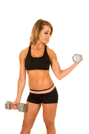 A fit woman looking down at her arm, while she is lifting weights.の写真素材