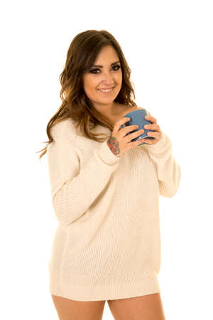 A woman in her white sweater, drinking her mug of coffee.の写真素材