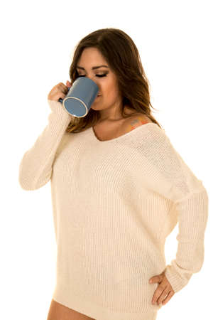 A woman in her sweater drinking her drink.の写真素材