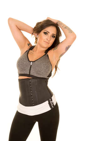a woman in her fitness clothes and corset with her hands in her hair.の写真素材