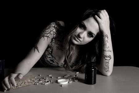 A woman looking with a sad expression, with her hand on a pill bottle.の写真素材