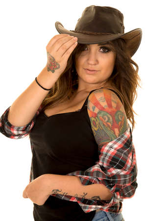 A cowgirl in her plaid shirt and western hat with her tattoo off of her shoulder.の写真素材