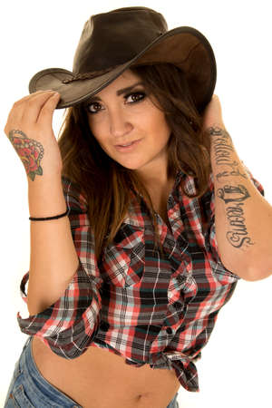 A cowgirl in her plaid top and western hat, with her tattoo on her arm.の写真素材