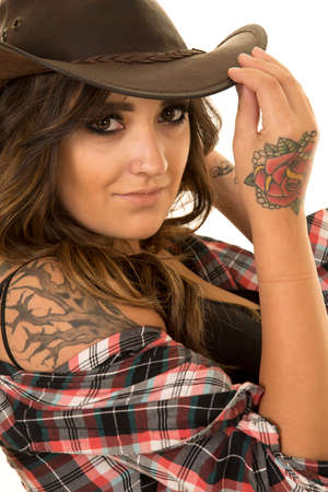 A woman in her plaid shirt, and western hat, with her tattoos showing.の写真素材