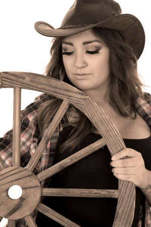 a cowgirl looking down at a wagon wheel with tattoos on her body.の写真素材
