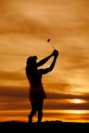 a silhouette of a woman swinging in the outdoors.の写真素材