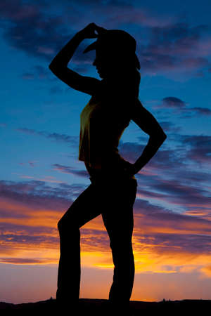 a silhouette of a woman in her western hat, touching the hat.の写真素材