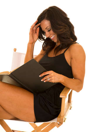 a woman sitting and relaxing in her chair reading a book and laughing.の写真素材