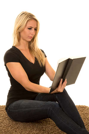 a woman sitting on her carpet reading her book.の写真素材