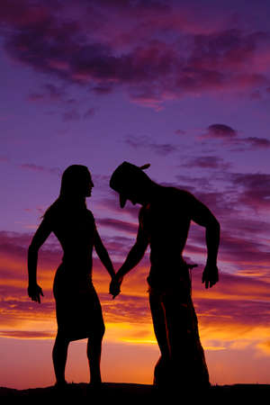 a silhouette of a woman holding hands with her cowboy.の写真素材