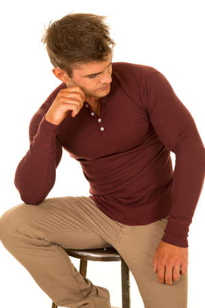 A man sitting on a stool with his head turned thinking.の写真素材