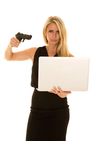 a woman with a upset expression, ready to shoot her laptop with her pistol.の写真素材