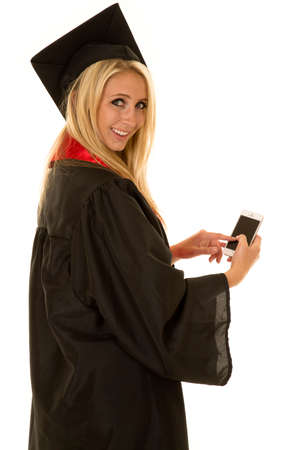 A woman with a big smile holding on to her cell phone sending a text out.の写真素材