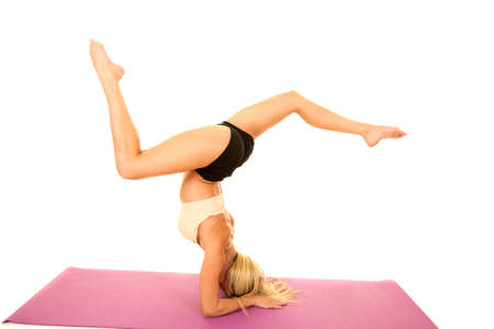 A woman in her fitness clothing doing a head stand showing off her strength and balance.の写真素材