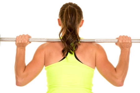 A woman with a bar across her back lifting weights.の写真素材