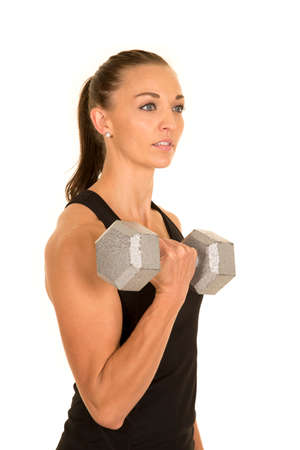 a woman in her tank top working out with weights, with a serious expression.の写真素材
