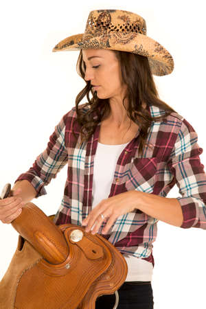 a cowgirl looking down at her saddle with a serious expressions.の写真素材