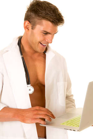 A Doctor looking down at his laptop with a smile on his face.の写真素材