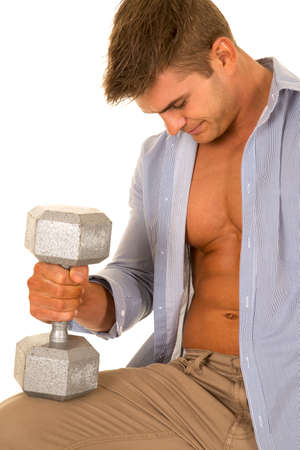 a man with his shirt unbuttoned holding a weight on his knee.の写真素材