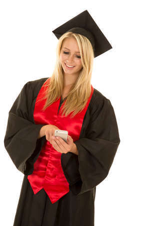 a woman with a smile graduating and looking down at her cell phone.の写真素材