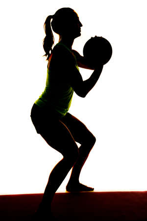 a silhouette of a woman doing a squat with a weighted medicine ball.の写真素材