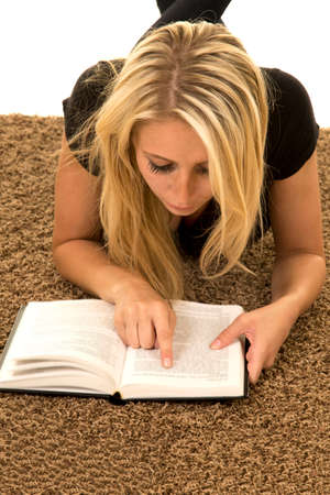 a woman laying on the carpet reading her book.の写真素材