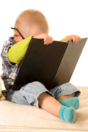 a young boy with his face hidden in his book.の写真素材
