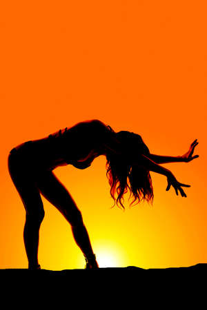 A silhouette of a woman bending over posing.の写真素材