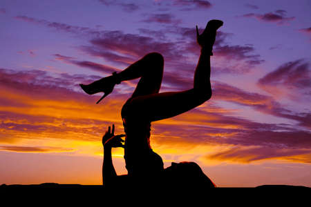 A silhouette of a woman laying back with her legs kicked up.の写真素材